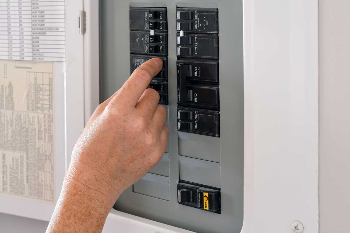 Hand Adjusting A Circuit Breaker In A Home